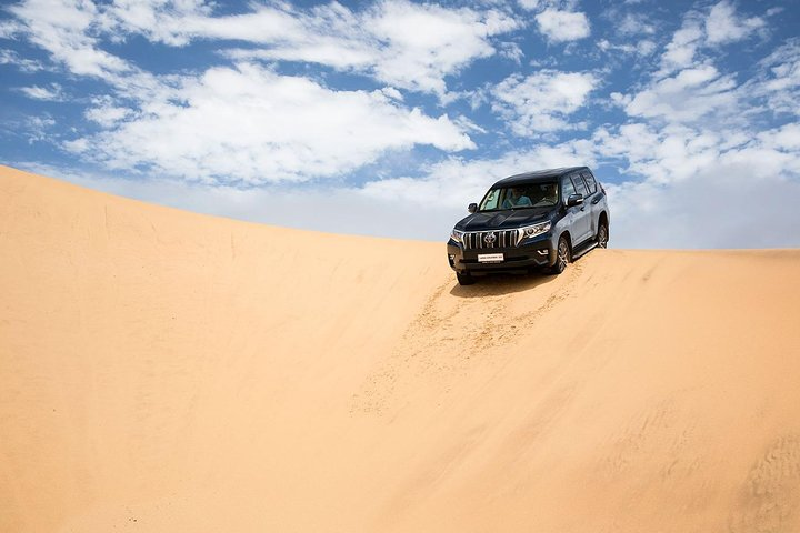 Experience the excitement of mastering the UAE's stunning desert landscapes in a powerful 4X4 navigating dunes while capturing unforgettable moments under the vast sky.